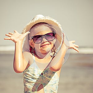 Happy little girl in the hat standing on the beach