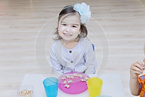 Happy little girl having breakfast with her friend