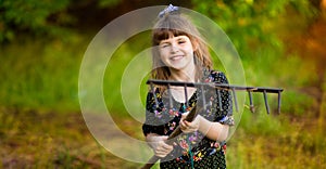 Happy little girl help parents in garden with rake