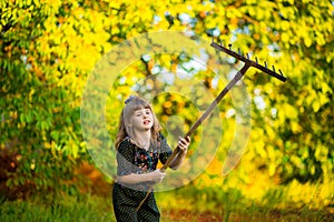 Happy little girl help parents in garden with rake. Seasonal garden work