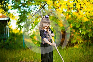 Happy little girl help parents in garden with rake. Seasonal garden work