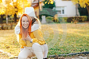 Happy little girl and her mother playing in the autumn park. Lovely family laughing on autumn walk