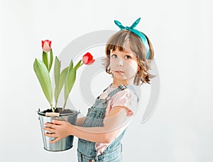 Happy Little girl is holdinf red tulips against a white background. Spring and Easter concept