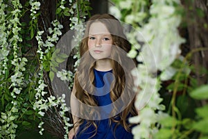 Happy little girl holding decorative bird cage full of flowers. Studio shot in provence style interior