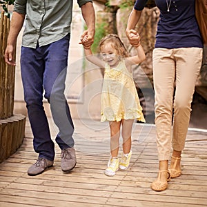 Happy, little girl and holding hands with parents for bonding, adventure or field trip. Excited child or kid walking