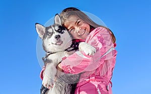 Happy little girl holding her puppy dog husky