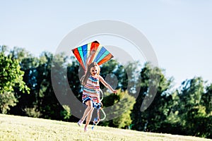 Happy little girl holding a kite and running