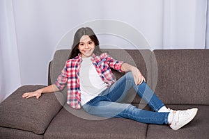 Happy little girl at home. Childrens day. Happy child relax on sofa. Casual childrens fashion. Little girl relas at home