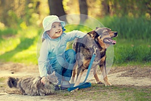 Happy little girl hugging dog and cat