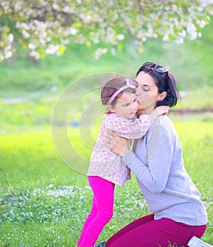 Happy little girl hugging and kissing her mother