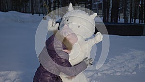 Happy little girl hugging snowman on evening winter walking in country village