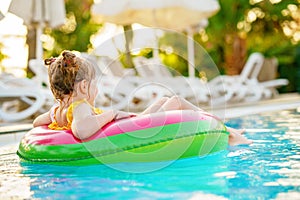 Happy little girl with inflatable toy ring float in swimming pool. Little preschool child learning to swim and dive in