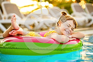 Happy little girl with inflatable toy ring float in swimming pool. Little preschool child learning to swim and dive in