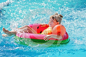 Happy little girl with inflatable toy ring float in swimming pool. Little preschool child learning to swim and dive in