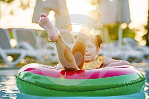 Happy little girl with inflatable toy ring float in swimming pool. Little preschool child learning to swim and dive in