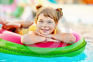 Happy little girl with inflatable toy ring float in swimming pool. Little preschool child learning to swim and dive in