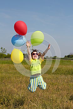 Happy little girl jumping with balloons