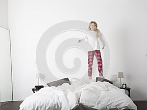 Happy little Girl jumping in bed