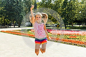 Happy little girl jumping in the park. little girl eating ice cream and having fun in the city