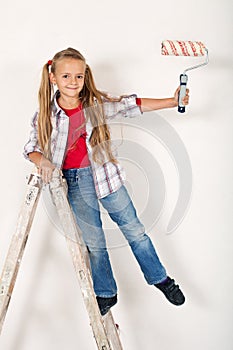 Happy little girl on a ladder with roller brush - repainting the