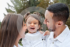 Happy little girl laught with her parents in the park photo