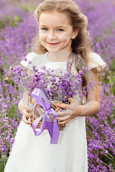 Happy little girl in lavender field with basket of