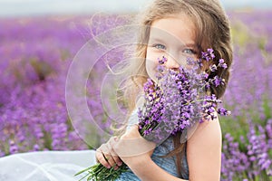 Happy little girl in lavender field with bouquet