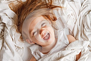 Happy little girl laying in laundry