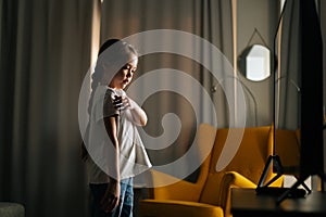 Happy little girl learning dance moves watching online video lessons on phone at home.