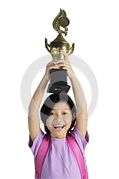 Happy little girl lifting her winning trophy