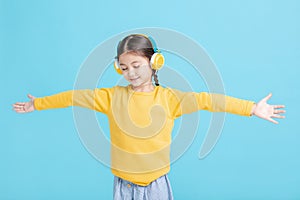 Happy little girl   listens to music in headphones