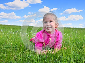 Happy little girl lying on grass