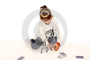 Happy little girl making house of cards isolated on white