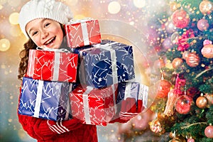 Happy little girl with many gifts near Christmas tree