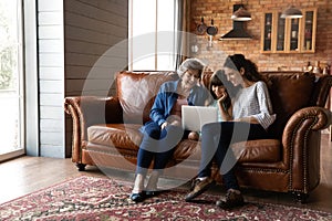 Happy little girl with mother and mature grandmother using laptop