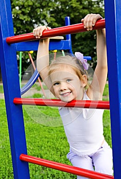 Happy little girl on outdoor playground equipment