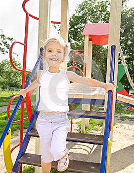 Happy little girl on outdoor playground equipment