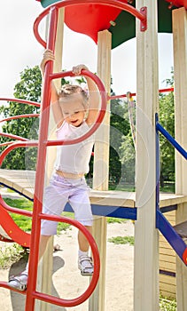 Happy little girl on outdoor playground equipment