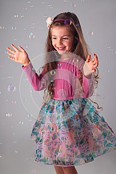 Happy little girl in party dress playing with soap bubbles portrait