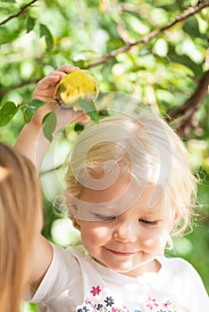 Happy little girl picking apple from tree