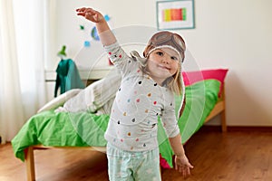 Happy little girl in pilot hat playing at home