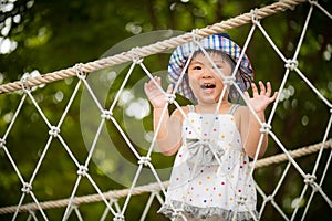 Happy little girl playing climbing on the rope bridge