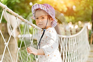 Happy little girl playing climbing on the rope bridge