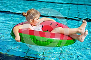 Happy little girl playing with colorful inflatable ring in outdoor swimming pool on sunny summer day. Preschool child