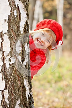 Happy little girl playing hide and seek outdoors