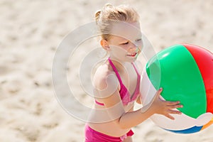 Happy little girl playing inflatable ball on beach