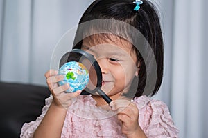 Happy little girl playing magnifying glass and globe ball. Children find countries on the world map. Concept of the kid is ready