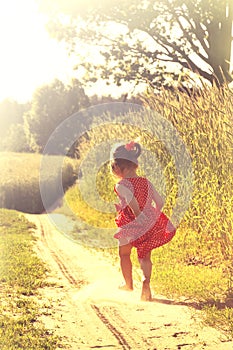 Happy little girl playing on meadow, sunset, summertime