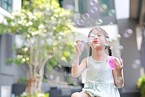 Happy little girl playing soap bubbles in garden