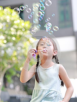 Happy little girl playing soap bubbles in garden